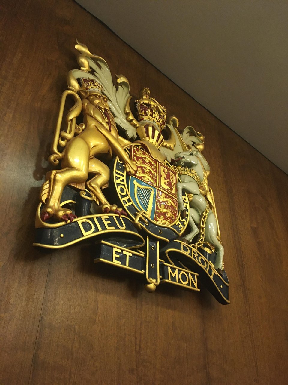 Royal Coat of Arms plaque on wood panelling, as mounted behind the judge in English and Welsh courtrooms